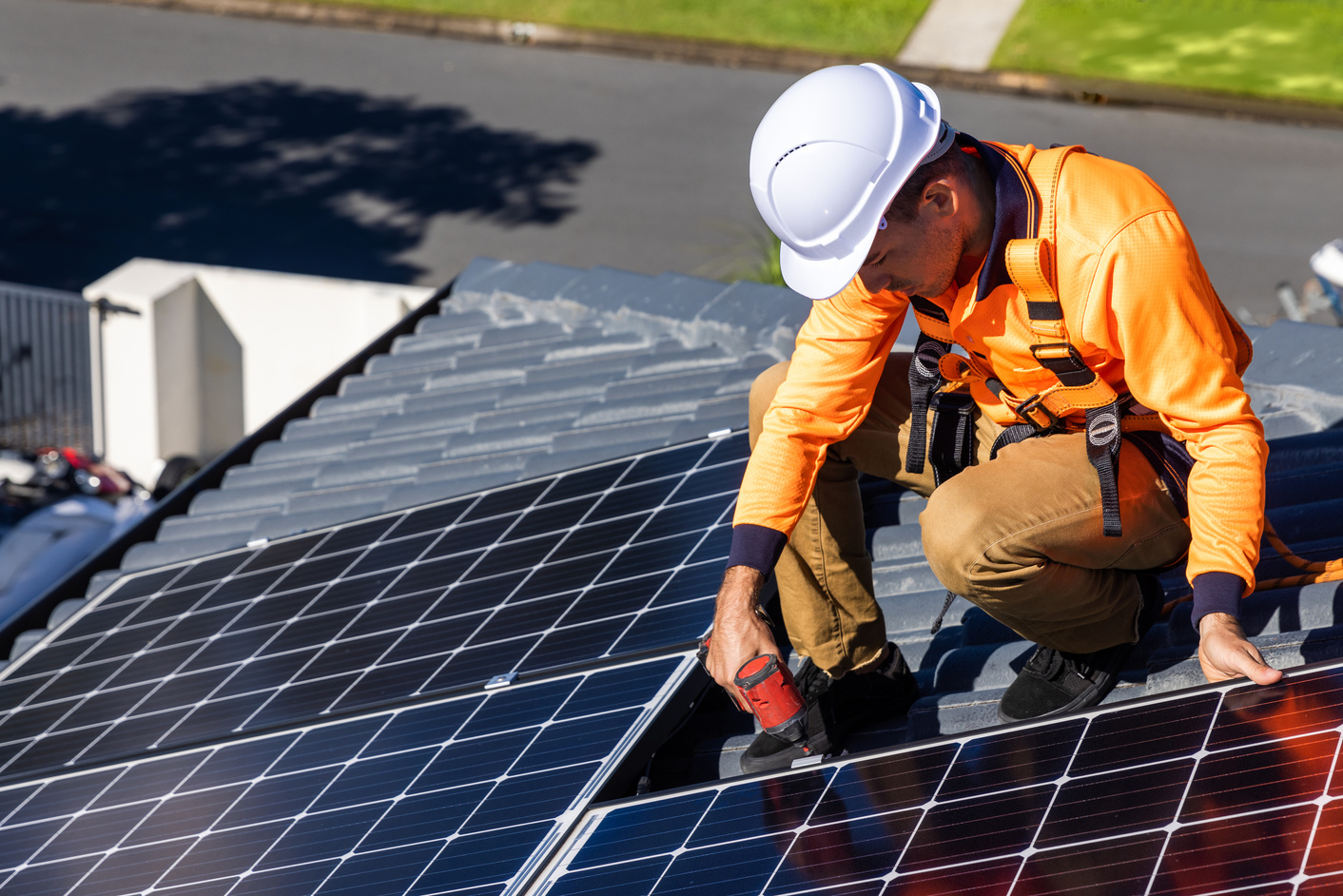 Solar panel technician with drill installing solar panels